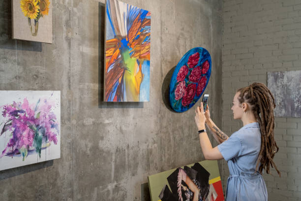 istock Woman photographing paintings in the phone 1366948708