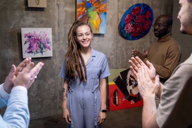 Young artist presenting the paintings in gallery