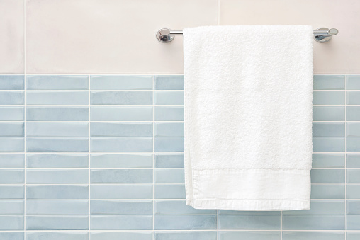 White fluffy bath towel hanging on wall rail in bathroom