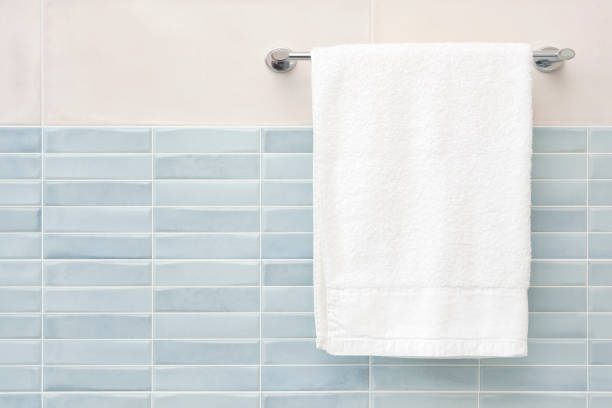 White fluffy bath towel hanging on wall rail in bathroom White fluffy bath towel hanging on wall rail in bathroom towel stock pictures, royalty-free photos & images