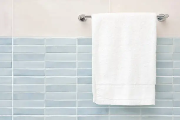 Photo of White fluffy bath towel hanging on wall rail in bathroom