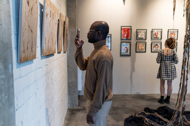 istock Man photographing artwork on the phone 1366948770