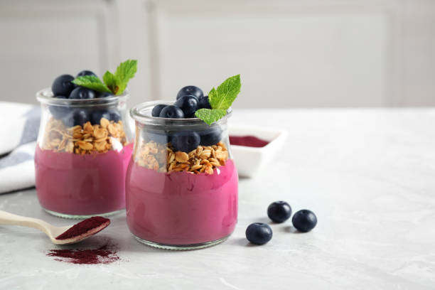 istock Tasty dessert with acai smoothie, granola and berries on marble table. Space for text 1366949616