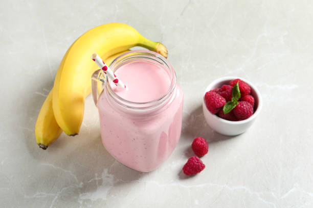 smoothie à la framboise fraîchement préparé dans un pot mason sur une table en marbre - raspberry milkshake photos et images de collection