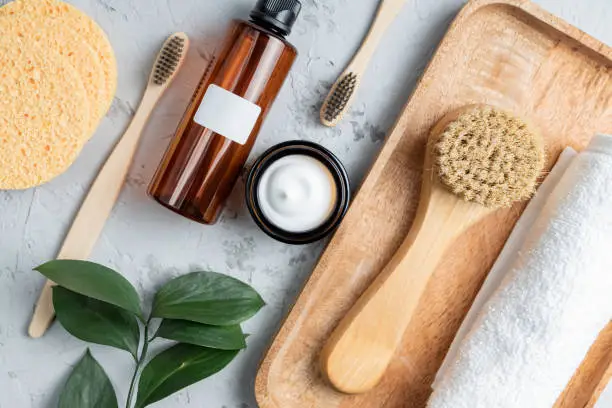 Photo of Natural SPA cosmetic products. Composition with bottles of essential oils, face cream, sponges, brushes and massage tools on concrete background. Zero waste concept