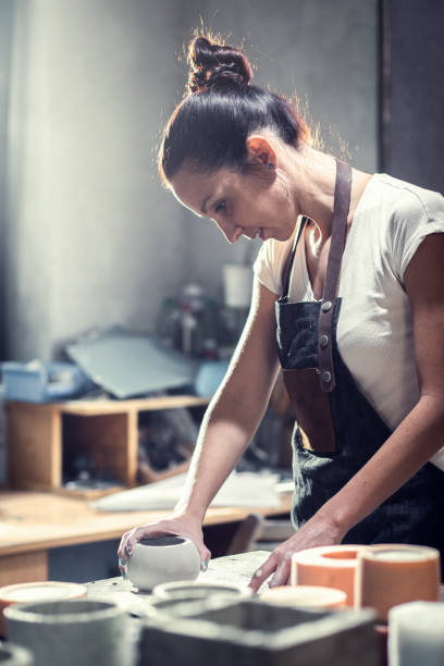 istock Craftswoman in apron working in her workshop making decorative concrete vase. 1366951727