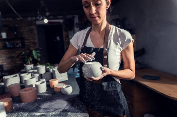 istock Craftswoman in apron working in her workshop making decorative concrete vase. 1366951784