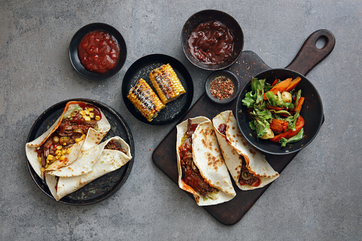 Mexican slow cooker shredded beef tacos. Flat lay top-down composition on concrete background.