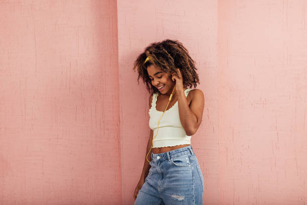 istock Smiling female enjoying music while standing against wall 1366953197