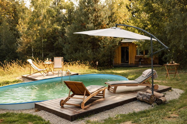 Two women in vacation enjoying a beautiful evening with a drink by poolside of their rental house.