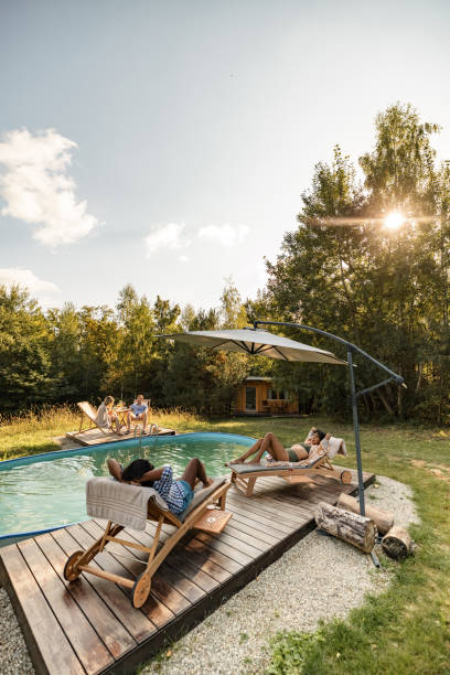 istock Two Couples Relaxing By The Swimming Pool In Nature 1366955570