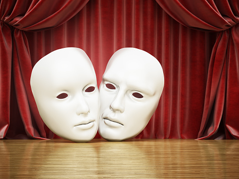 White male and female masks standing on the stage against red curtain.