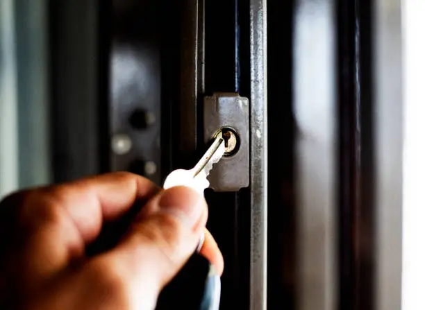 A close-up of a man holding a key to open a security gate