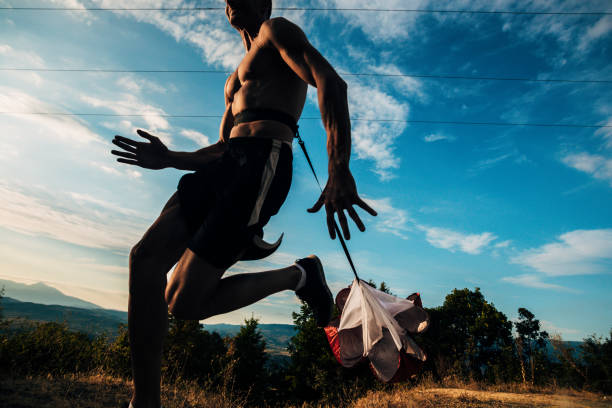 istock Sporty man jogging over blue sky with resistance parachute 1366958072