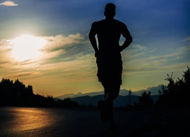 istock Sporty man jogging over blue sky on mountain path 1366958094