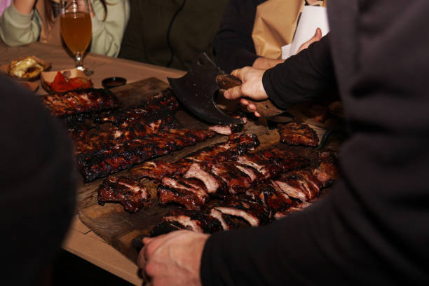 istock Waiter chops juicy barbecue ribs when serving to restaurant customers 1366961764