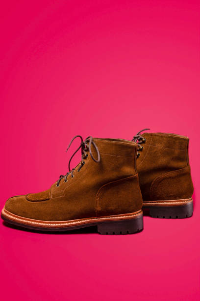 istock Footwear Concepts. Tan Brown Suede Split Toe High Boots Closeup With Visible Leather Texture Placed Over Pink Red Background. 1366962050