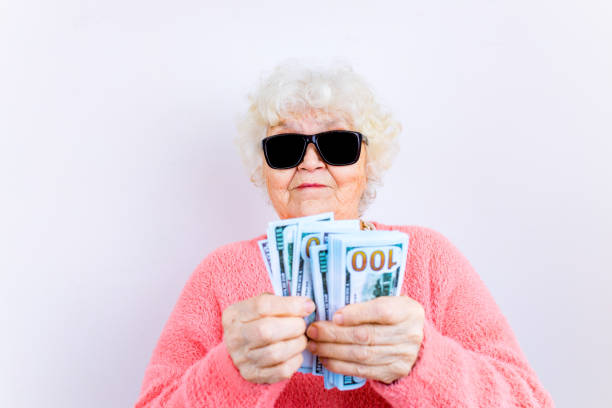 anciana rubia usa suéter de pinza y gafas de sol que muestran dinero aislado fondo blanco - spending money fotos fotografías e imágenes de stock