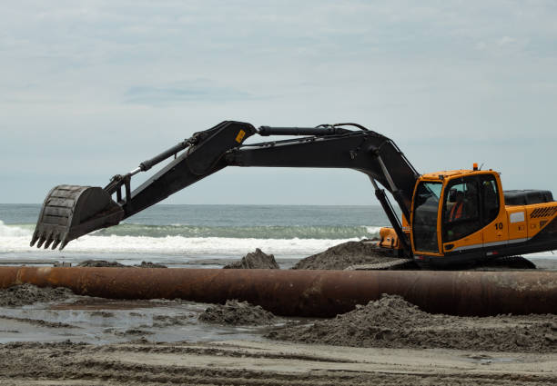 Excavator Excavator on the beach preparing soil for dredging pipe installation. oilsands stock pictures, royalty-free photos & images