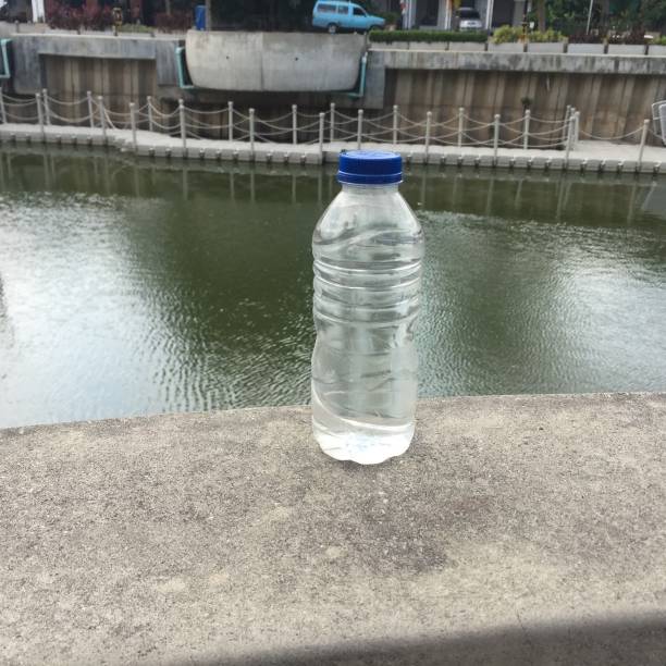 istock Bottle of mineral water on a clear river background. 1366971999