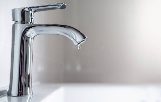faucet with a drop of water against a white sink. - sink imagens e fotografias de stock