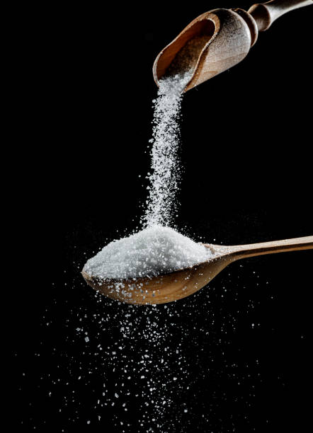 White refined sugar crystals falling down into the wooden spoon at black background. White refined sugar crystals falling down into the wooden spoon at black background. carbohydrate food type stock pictures, royalty-free photos & images