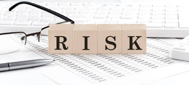 istock RISK written on wooden cube with keyboard , calculator, chart,glasses.Business concept 1366974026