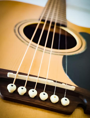 Acoustic guitar strings in the foreground seen from a lower plane