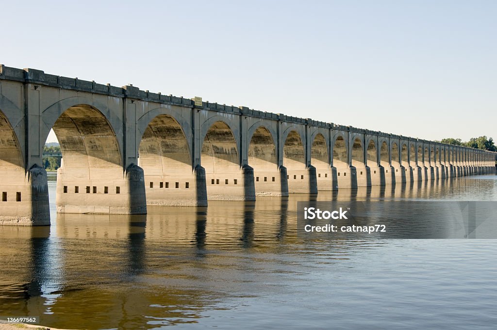 Bridge Arches in Long Perspective Bridge arches over the Susquehanna River in Harrisburg PA showing long perspective across the water, shot in early morning, carries Norfolk Southern Railroad tracks. Arch - Architectural Feature Stock Photo