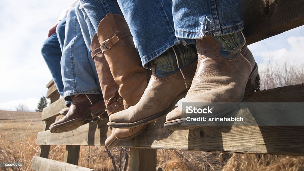 Cowboy Boots Cowboys and cowgirls sitting on wooden fence. Cowboy Boot Stock Photo