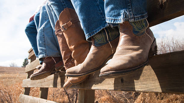 Cowboy Boots Cowboys and cowgirls sitting on wooden fence. cowboy boot stock pictures, royalty-free photos & images