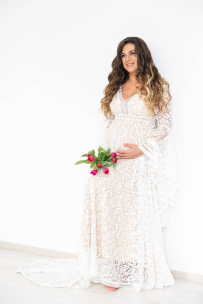 mujer embarazada con el ramo de flores en el vestido blanco. - human pregnancy flash fotografías e imágenes de stock