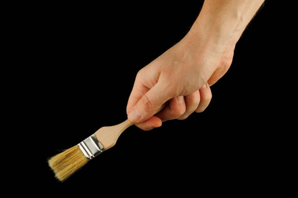 istock Paint brush in hand on a black background 1366981303