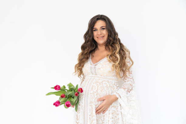 mujer embarazada con el ramo de flores en el vestido blanco. - human pregnancy flash fotografías e imágenes de stock