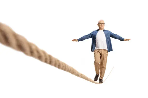 Full length shot of a casual mature man with walking over tightrope isolated on white background