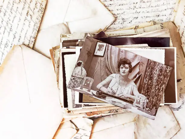 Pile of vintage photographs on top of old letters. High-view-angle image of photographs and letters from the beginning of the 20th century.