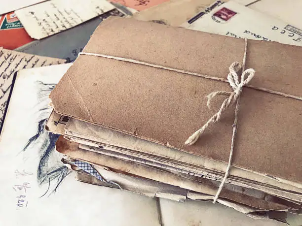 Old package made of carton and tied with a string on top of vintage letters and documents.