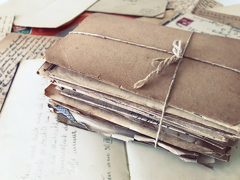 Package of old letters tied with a string on top of a vintage journal and open letters