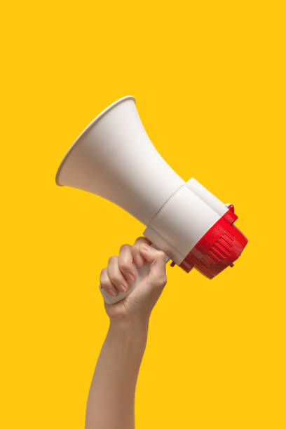 istock Megaphone in woman hands on a yellow background. 1366988535