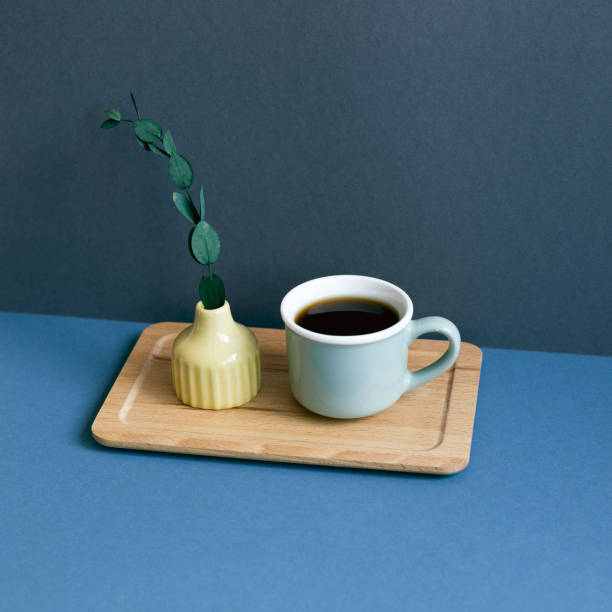 Cup of coffee and eucalyptus leaf on table. navy blue wall background