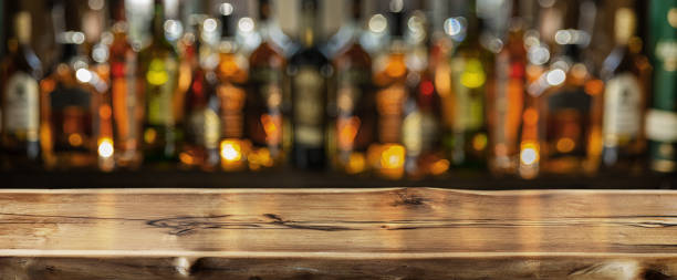 Wooden board and beautiful bokeh shelves with alcohol bottles at the background. stock photo