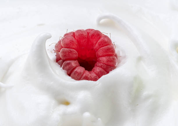 Fresh raspberry in the yoghurt or cream. Close-up.