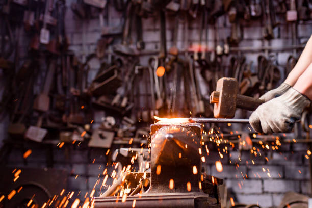 istock Authentic blacksmith man forges a metal product in dark indoors studio 1366989421