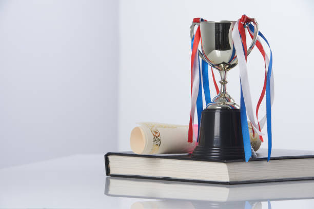 trophy, roll of certificate and book   against white background