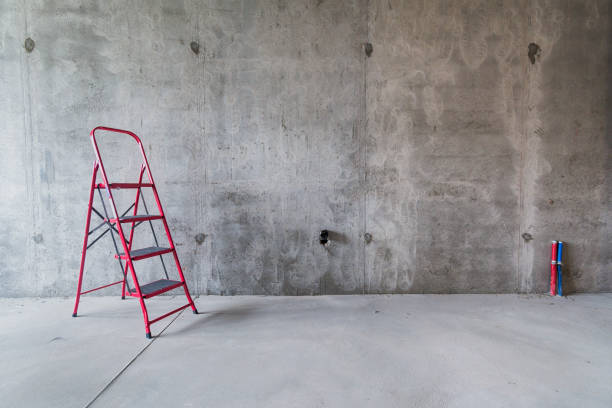 istock Red ladder against concrete wall of room interior under construction 1366993381