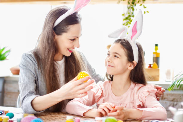 istock Mom and daughter wearing bunny ears decorating Easter eggs. 1366995010