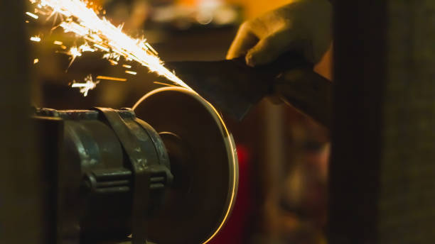 sharpen the knife on the abrasive wheel, sparks fly from grinding metal - bilemek stok fotoğraflar ve resimler