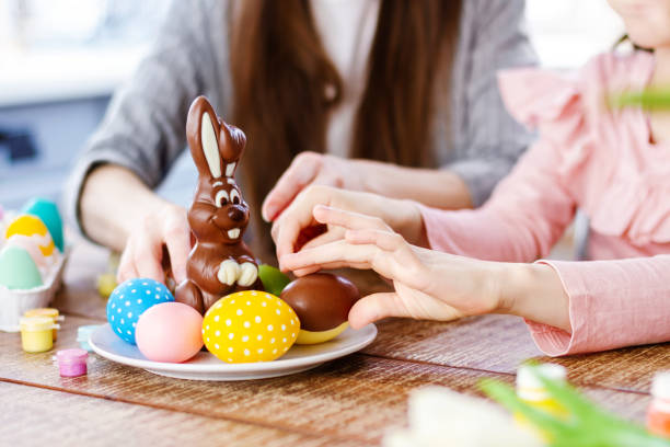девочка ест вкусного шоколадного кролика - vacations two generation family holiday easter стоковые фото и изображения