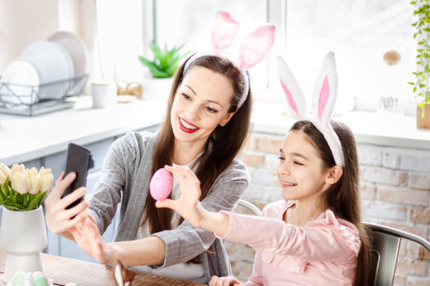 istock Mother and daughter wearing bunny ears doing selfie 1366995135