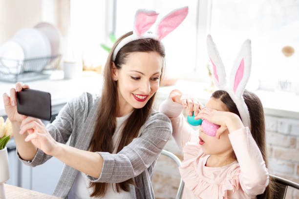 istock Mother and daughter wearing bunny ears doing selfie 1366995144